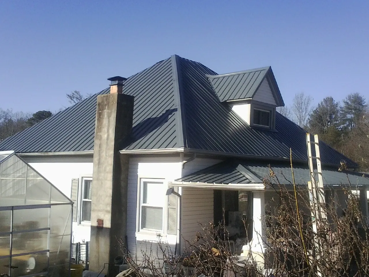 Dark blue standing seam metal roof on a white farmhouse with dormer — Slate & Tile Roof Repair by Roofing Brothers in Temecula