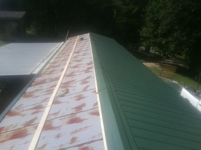 Old rusted panels beside newly installed green metal roofing — Wind Damage Roof Repair by Roofing Brothers in Temecula