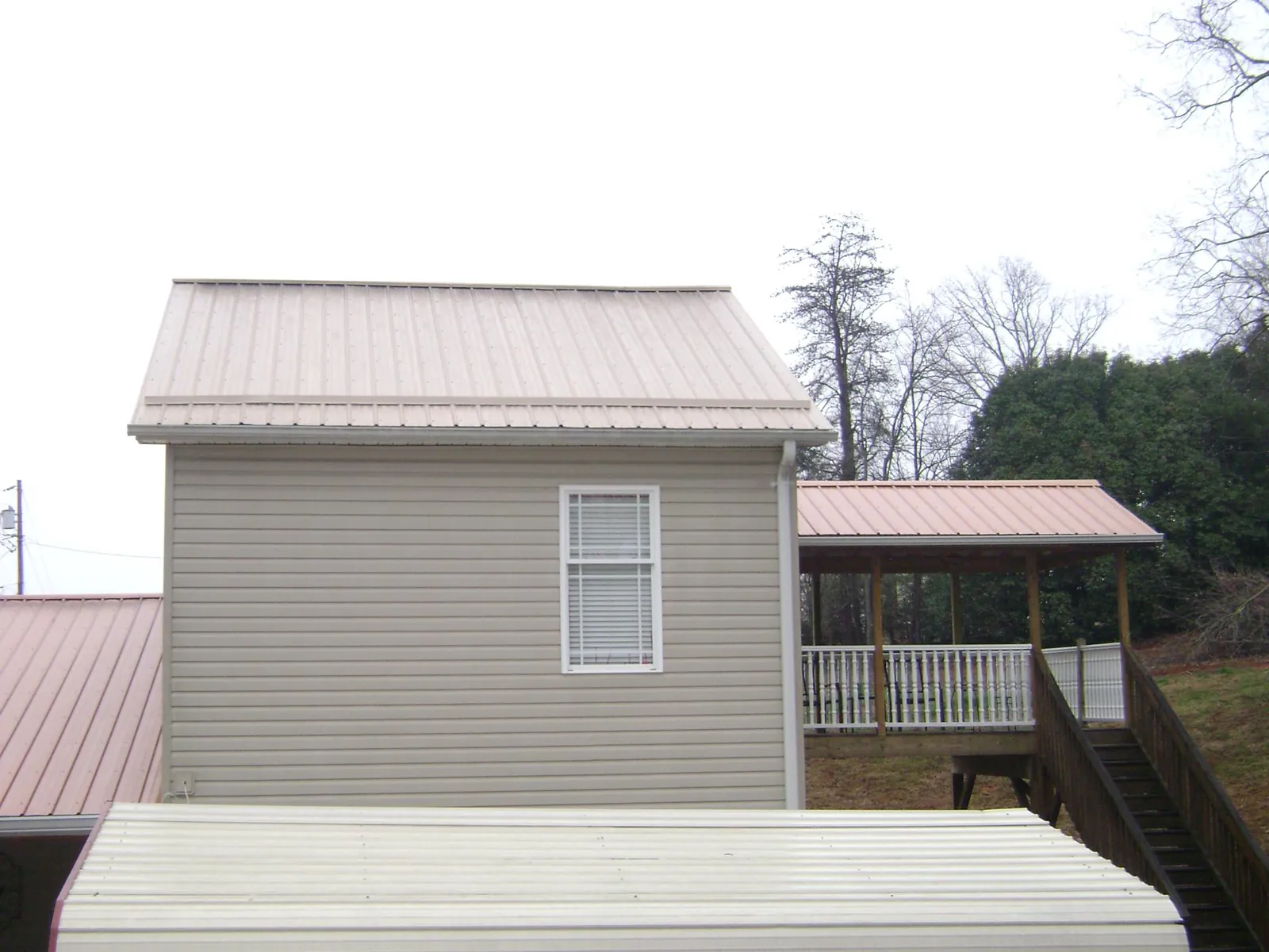 Tan metal roofs on a two story addition and attached porch, from a Roof Replacement job in Temecula